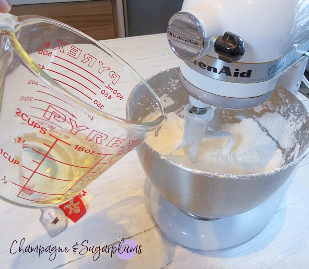 Adding champagne to icing in a stand mixer by Champagne and Sugarplums