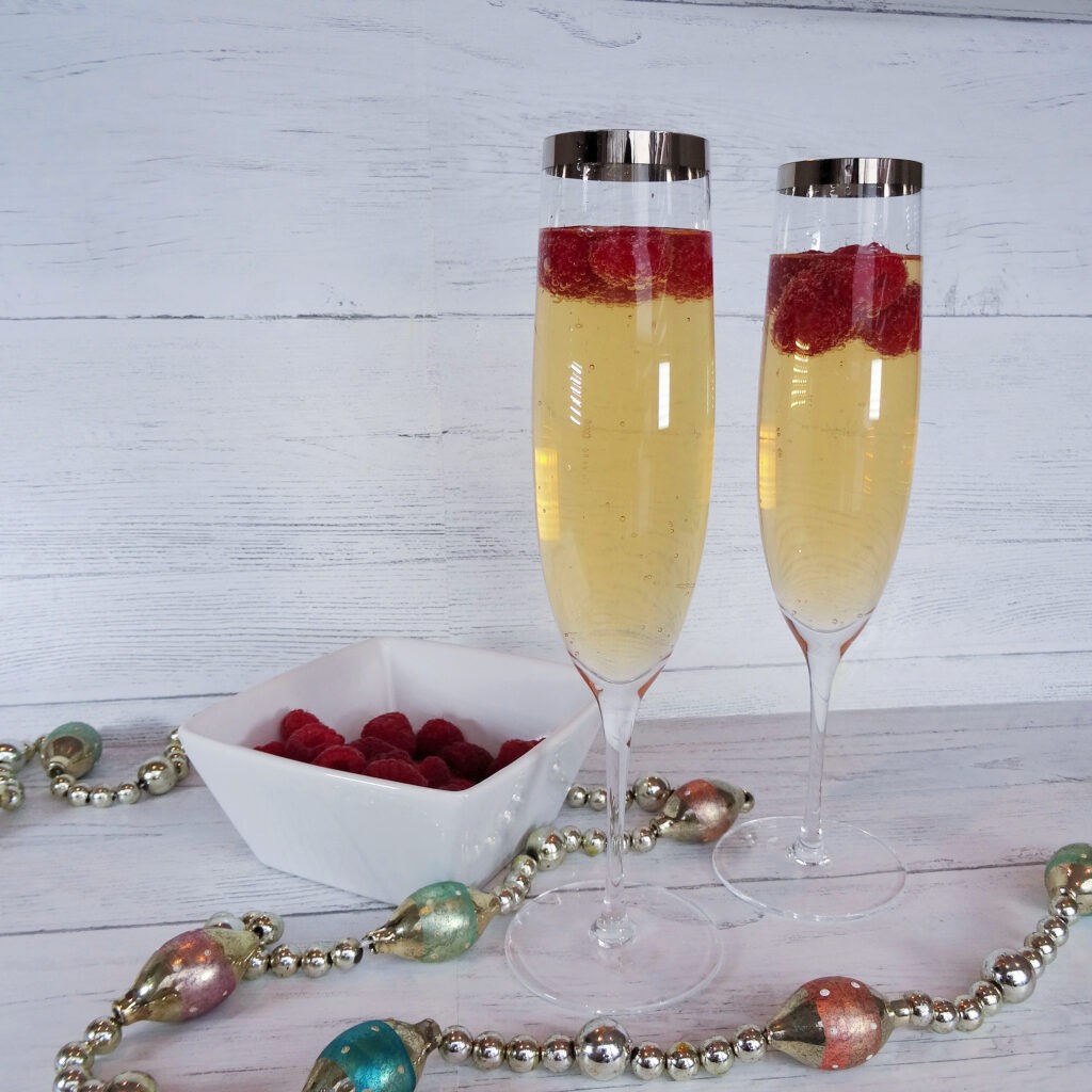 Cocktail with raspberries in a champagne flute on a white background by Champagne and Sugarplums