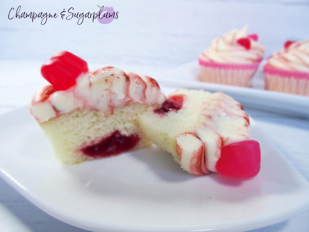 A Cherry Cupcake sliced in half to reveal cherry centre on a white background by Champagne and Sugarplums