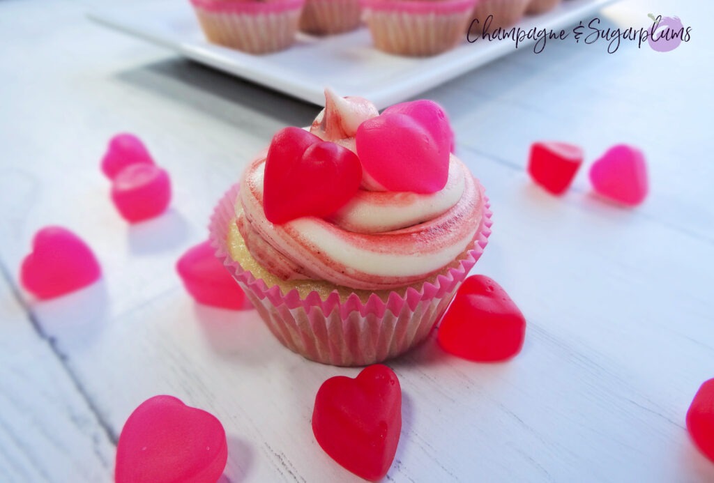 A Cupcake on a white background surrounded by red and pink candy hearts by Champagne and Sugarplums