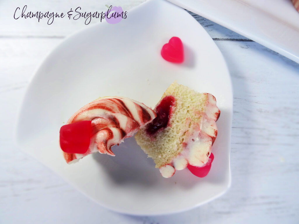 A Cherry Cupcake sliced in half to reveal cherry center on a white background by Champagne and Sugarplums