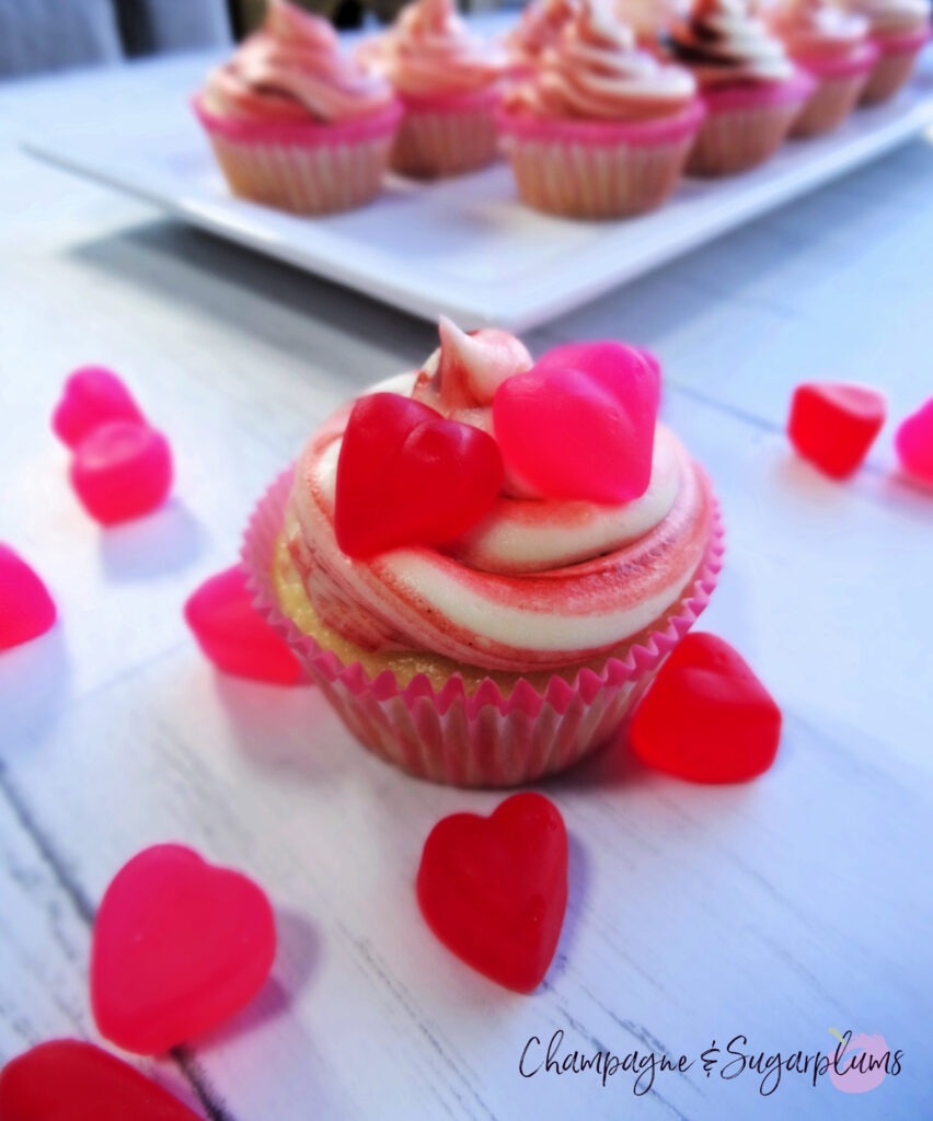 A Cherry Cupcake on a white background surrounded by red and pink candy hearts by Champagne and Sugarplums