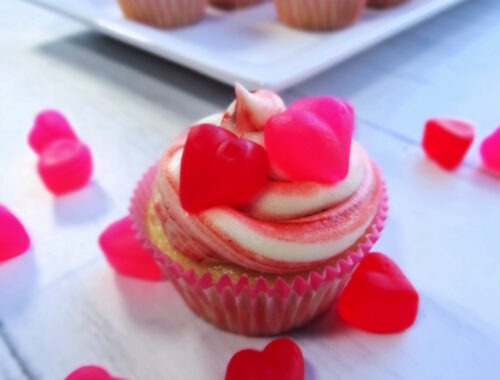 A Cherry Cheesecake Cupcake on a white background surrounded by red and pink candy hearts by Champagne and Sugarplums