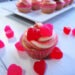 A Cherry Cheesecake Cupcake on a white background surrounded by red and pink candy hearts by Champagne and Sugarplums