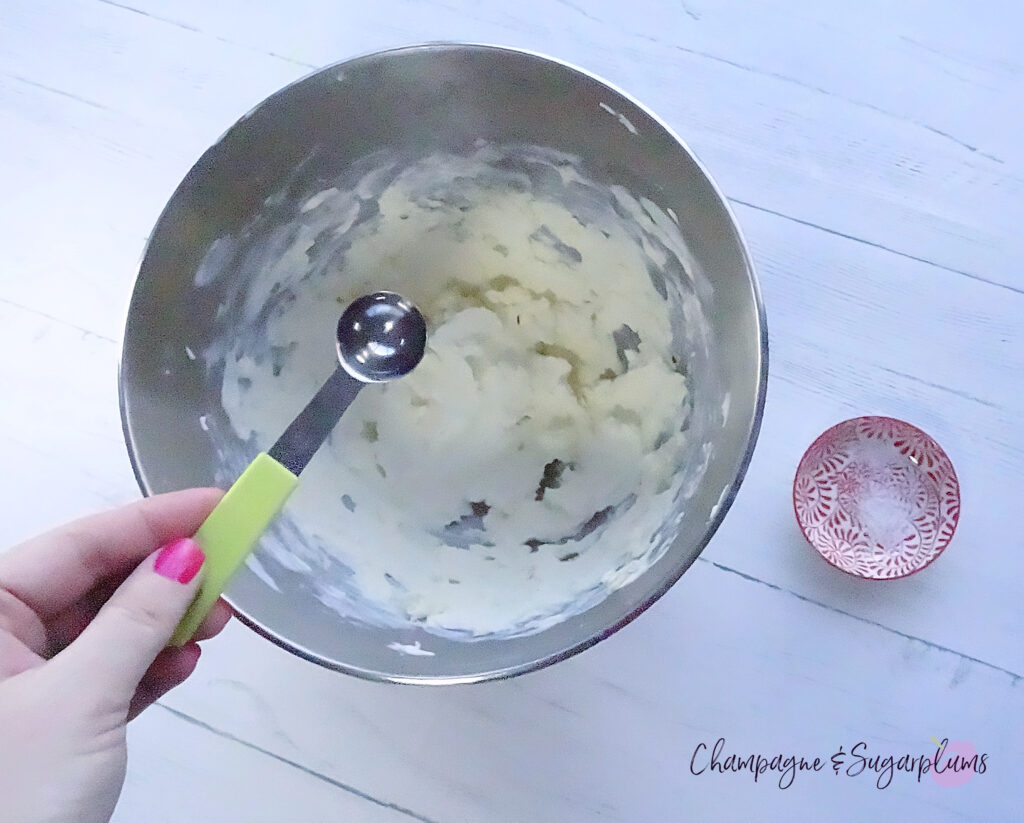 Making cream cheese icing in a metal mixing bowl on a white background by Champagne and Sugarplums