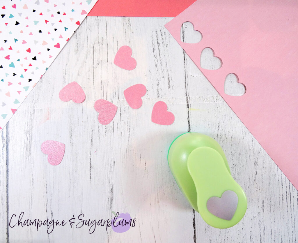 Pink paper hearts and a green heart punch on a white background by Champagne and Sugarplums