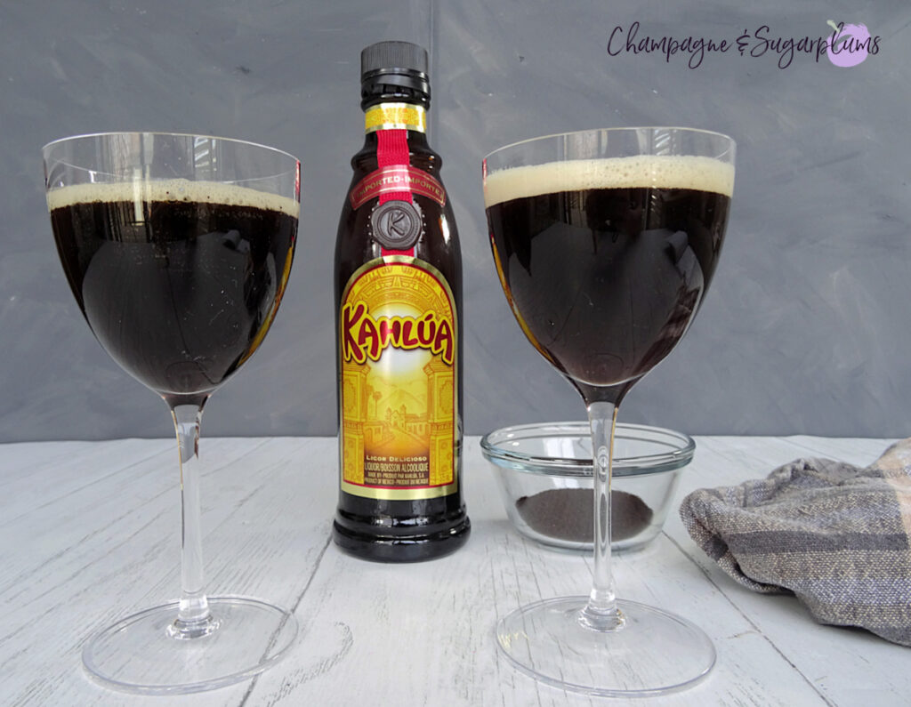 Espresso Martini with a bottle of Kahlua and a bowl of coffee grounds on a white and grey background by Champagne and Sugarplums