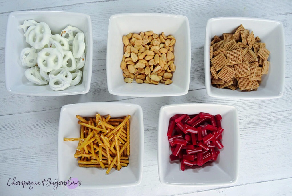 White bowls with ingredients for Snack Mix on a white background by Champagne and Sugarplums