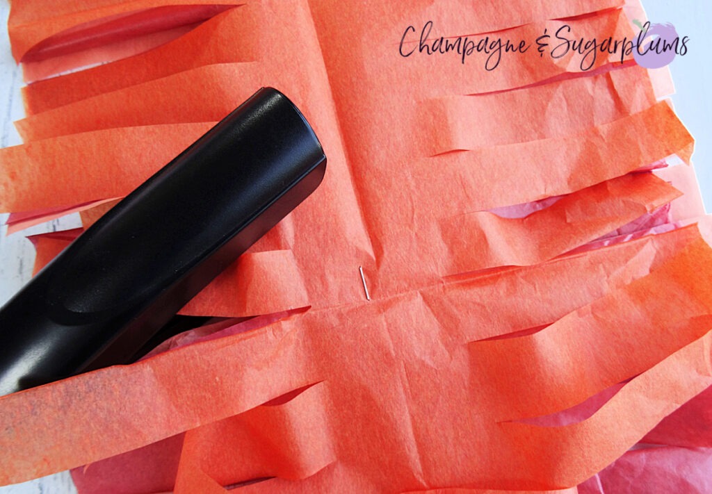 Adding staples to the middle of a Tissue Paper Garland by Champagne and Sugarplums