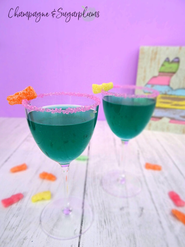 Two tipsy bunny cocktails in Nick and Nora glasses on a white background with sour candies by Champagne and Sugarplums