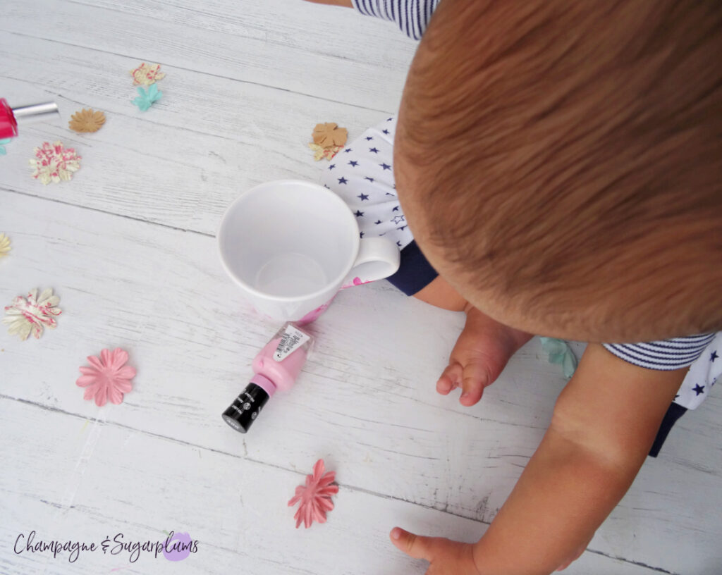 A baby playing with Nail Polish Marble Mugs on a white background by Champagne and Sugarplums