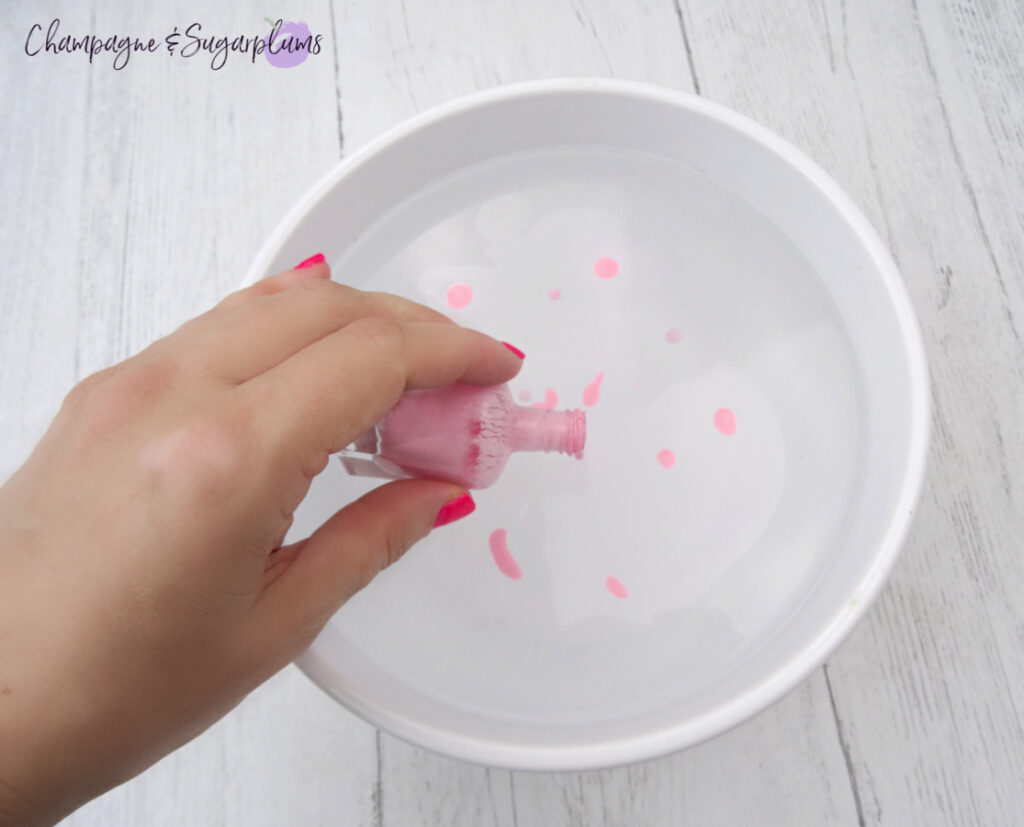 Pink polish in a white bowl with water on a white background by Champagne and Sugarplums