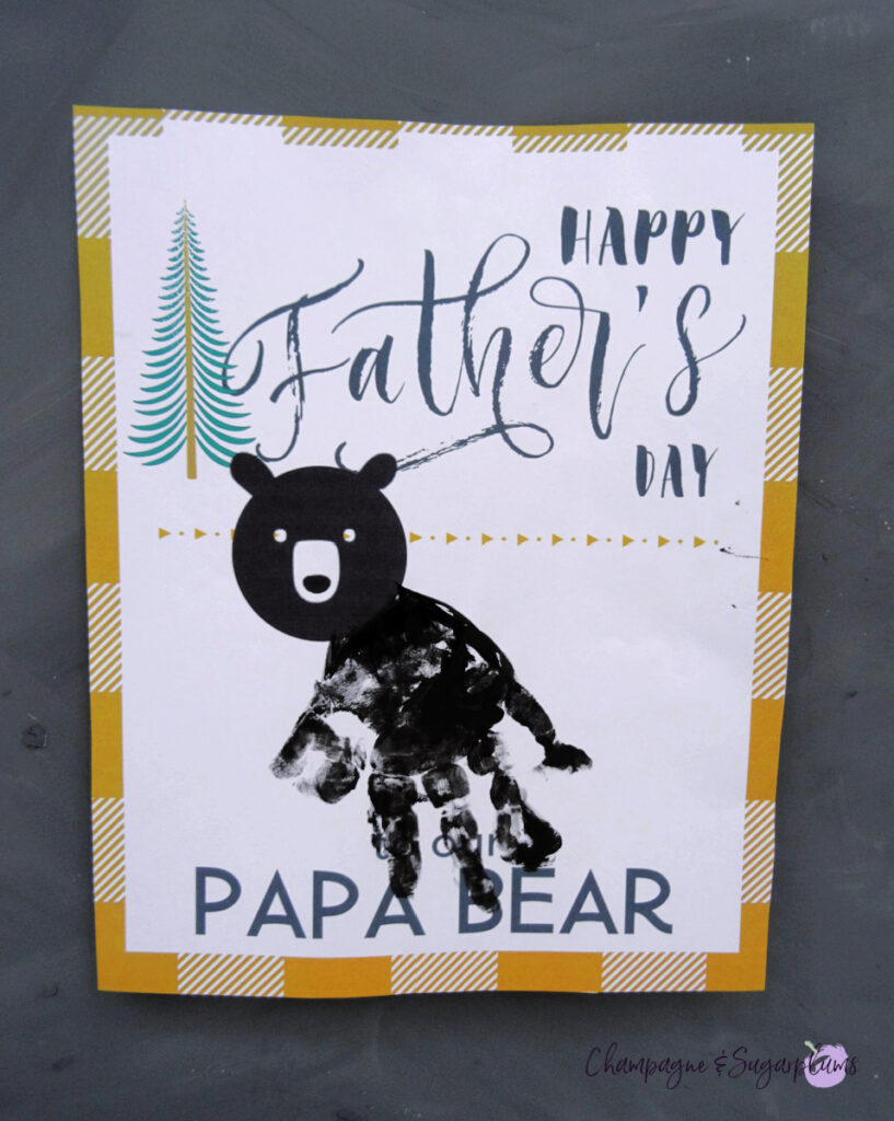 A printed paper with a yellow plaid border, black font, a bears head and a toddlers handprint by Champagne and Sugarplums