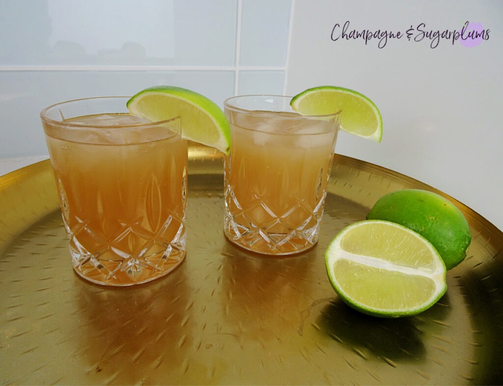 The Teacher's Pet Back to School Cocktail in highball glasses on a gold tray with limes by Champagne and Sugarplums