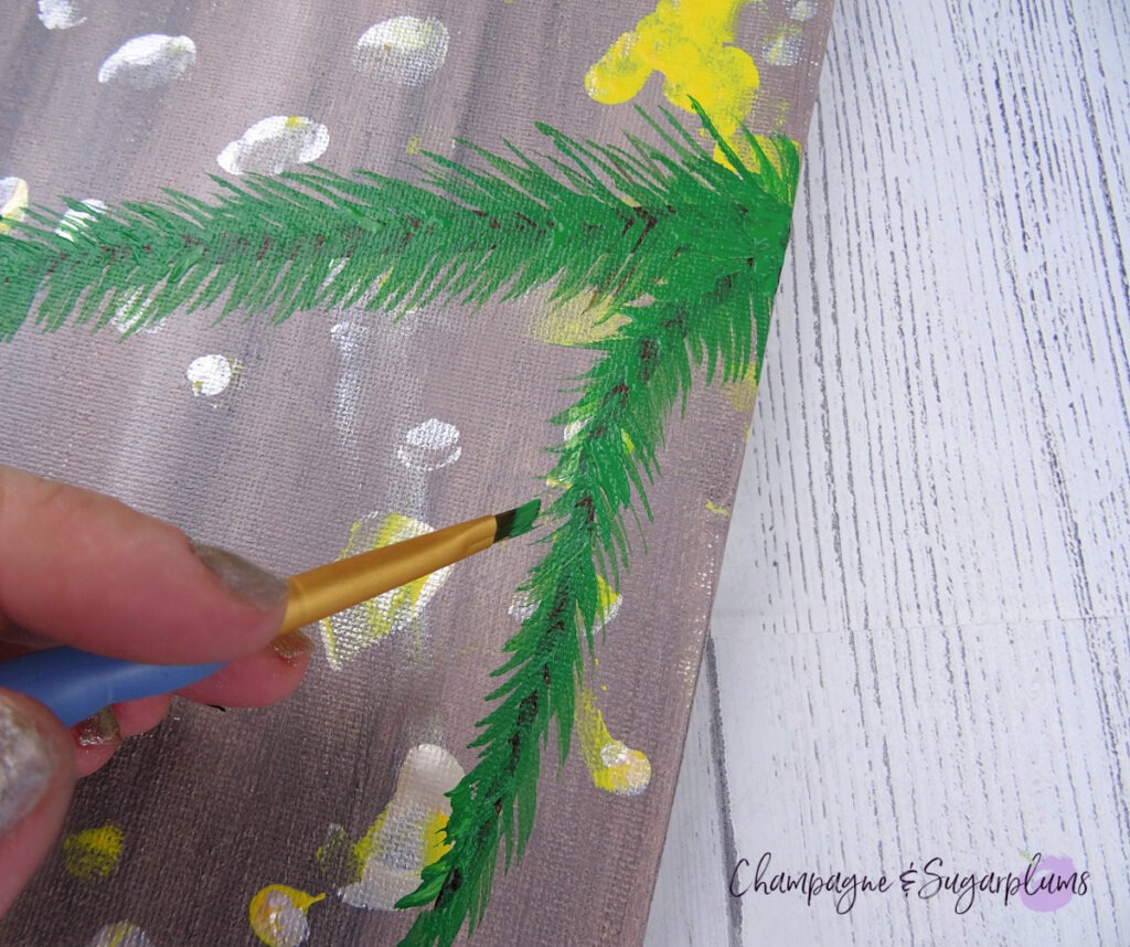 Painting green needles onto an evergreen branch by Champagne and Sugarplums