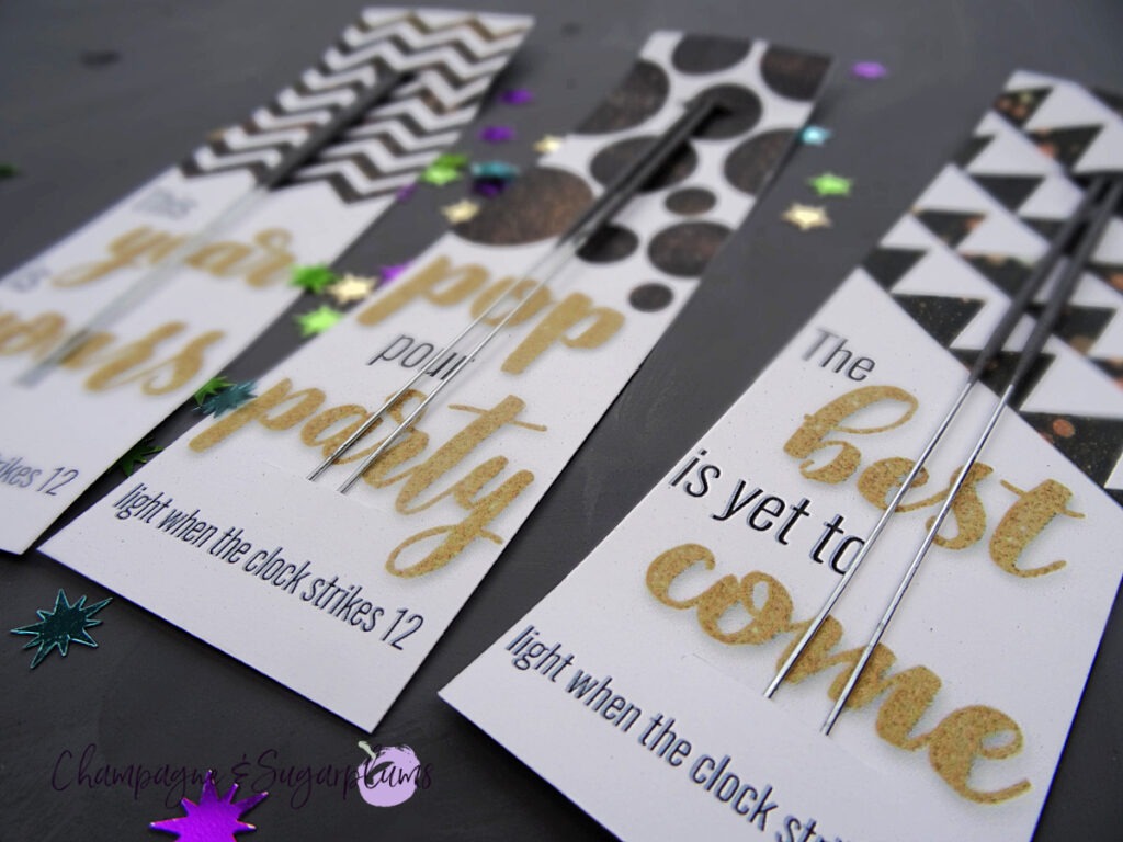 Three New Year's Eve Sparkler Cards on a gray background with star confetti by Champagne and Sugarplums